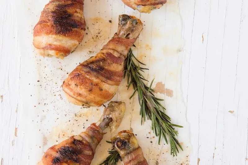Pilons de poulet à l'ail et au romarin en robe de bacon